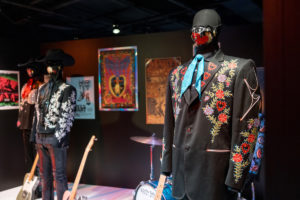 Una de las exhibiciones de The World of Marty Stuart.  Se pueden ver varios trajes de escenario, junto con carteles y grabados en el fondo.  También hay varios instrumentos en exhibición.